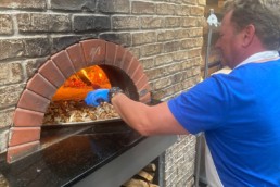 Craft 64 Josh Ivey putting pizza in Wood Fired Oven
